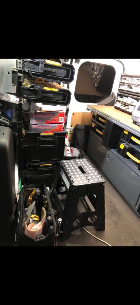 Interior of a locksmith service van showing organized tool storage, including toolboxes and a folding stool, emphasizing mobile locksmithing convenience for transponder key programming in St. Louis.