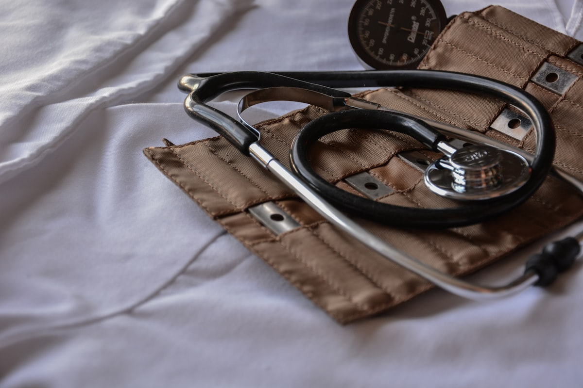 Stethoscope and blood pressure cuff on a white surface, representing medical equipment for health assessments.